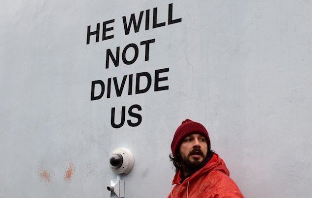 US actor Shia LaBeouf(L)is seen during his He Will Not Divide Us livestream outside the Museum of the Moving Image in Astoria, in the Queens borough of New York January 24, 2017 as a protest against President Donald Trump. LaBeouf has installed a camera at the Museum of the Moving Image in New York that will run a continuous live stream for the duration of Trumps presidency. LaBeouf is inviting the public to participate in the project by saying the phrase, He will not divide us, into the camera. / AFP / TIMOTHY A. CLARY (Photo credit should read TIMOTHY A. CLARY/AFP/Getty Images)